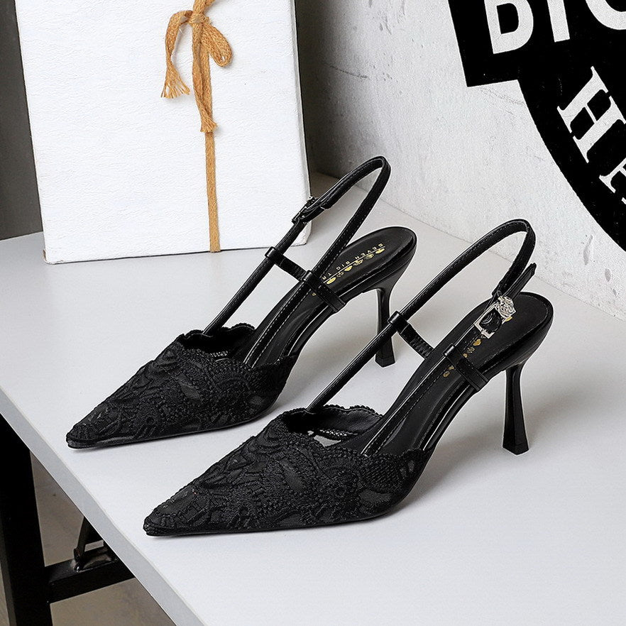 Black lace high-heeled shoes on a white surface with a blurred background