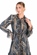 A woman modeling a long-sleeve ruffled dress with a blue-gray and beige abstract pattern, set against a plain white background.