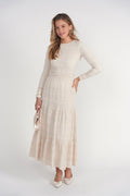 Woman wearing a long beige dress with a white background