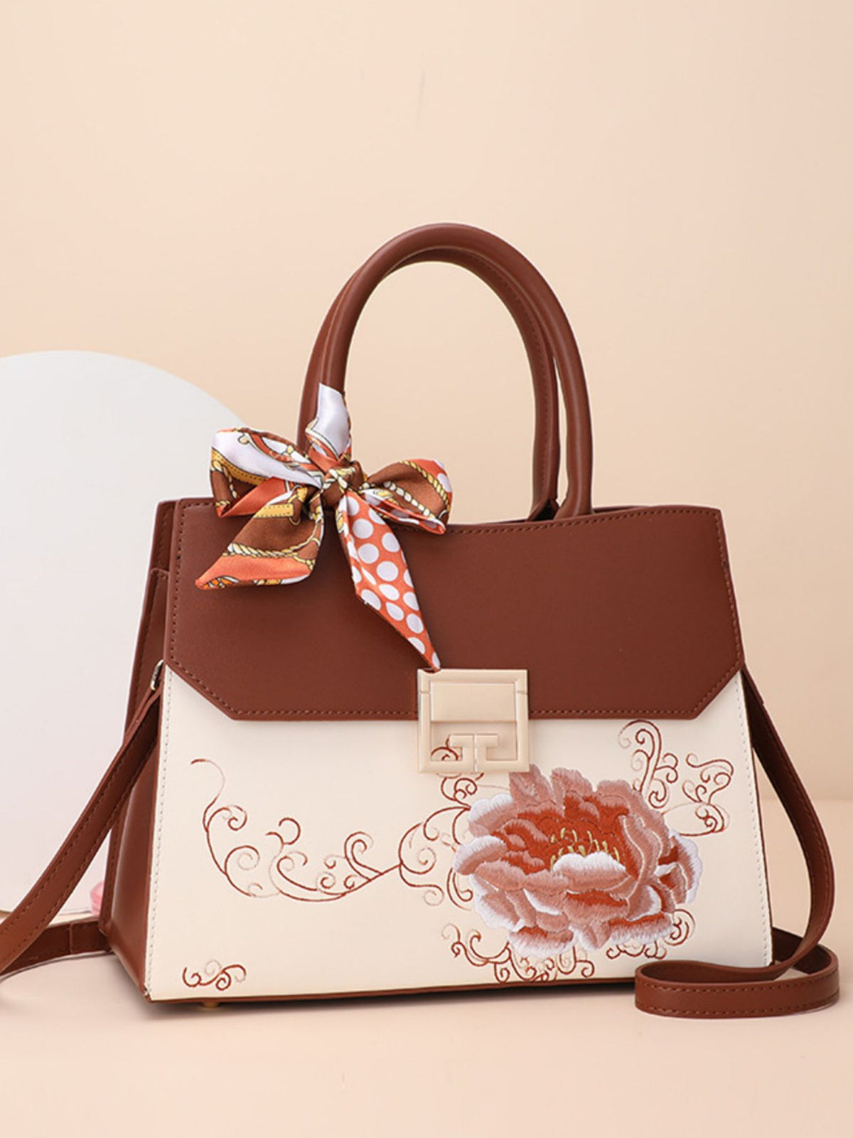 Brown and beige handbag with floral design and ribbon on a beige background