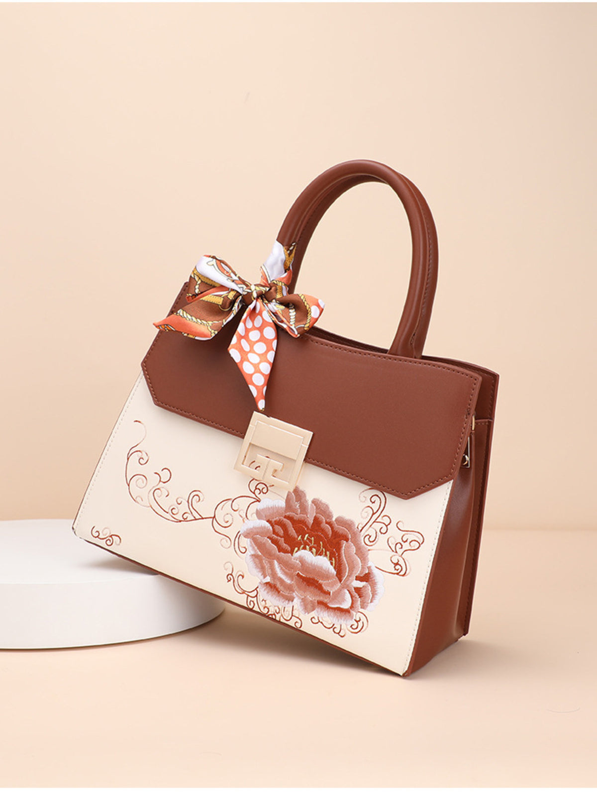 Designer handbag with floral design and decorative bow on a beige background