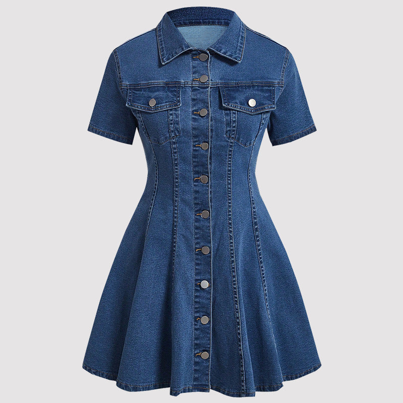 A short-sleeve blue denim dress with a collared neckline, button-front closure, and two chest flap pockets, shown on a plain light gray background.