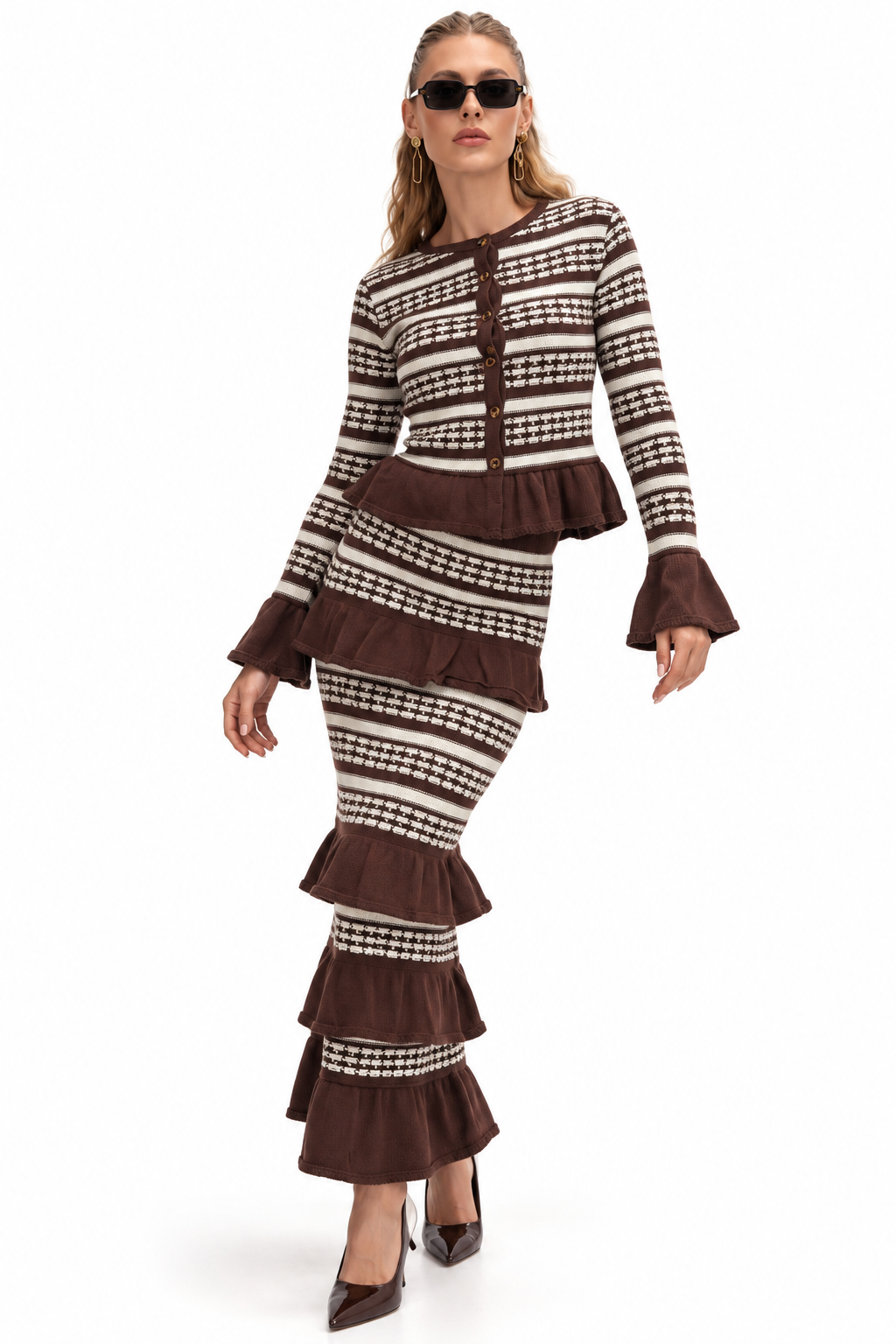 A woman modeling a matching two-piece knit set with a brown and cream houndstooth pattern, featuring a long-sleeve top with ruffled cuffs and a tiered skirt, against a plain white background.