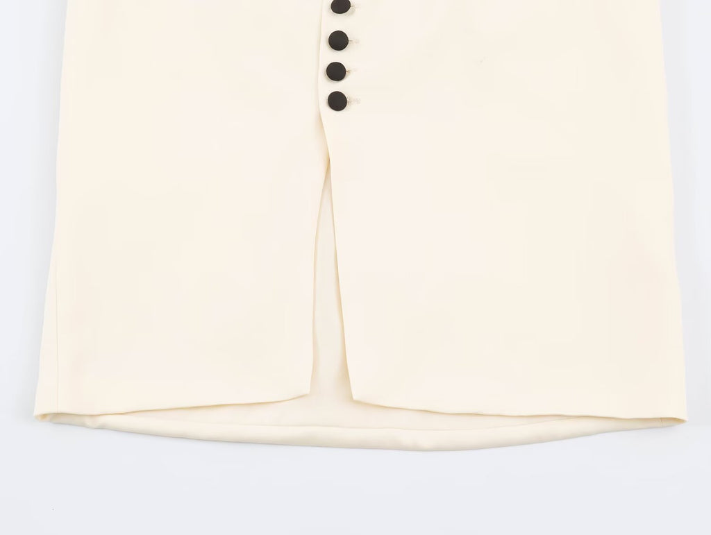 Close-up of a cream-colored garment with a front slit and a vertical row of black buttons, shown against a plain white background.
