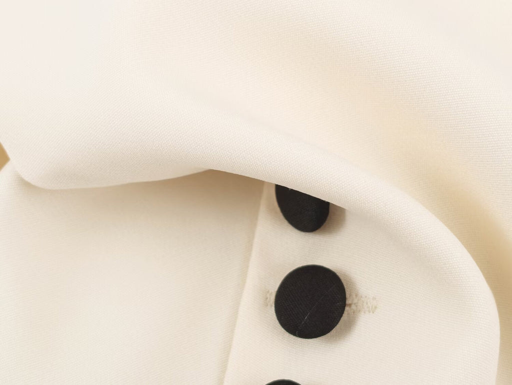 Close-up of an off-white or cream fabric surface with a curved fold and three visible black buttons.