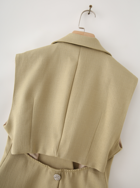 A beige sleeveless blazer vest with a structured collar and notched lapels, shown from the back on a wooden hanger against a plain white wall.