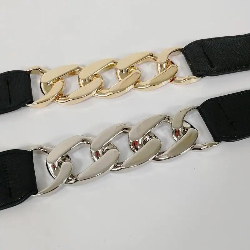 Two gold chain belts with black straps on a light gray background