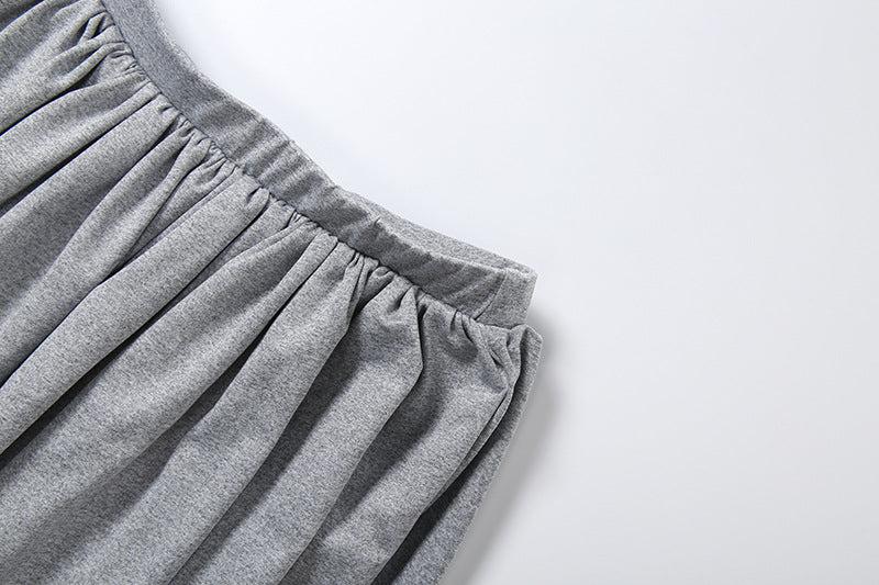 Close-up of a gray pleated fabric garment, showing the elasticized waistband and gathered texture against a plain light background.